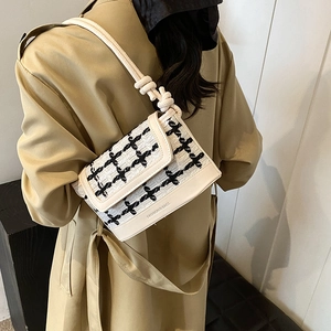 Chic tweed plaid shoulder bag in cream white with knot strap on a person's shoulder