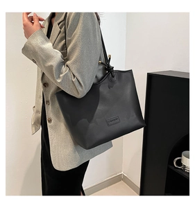 Détail d'un sac cabas noir minimaliste avec étiquette mode et boucles en métal doré