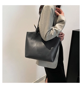 Détail du sac cabas en cuir noir avec bandoulière nouée et finitions métalliques dorées