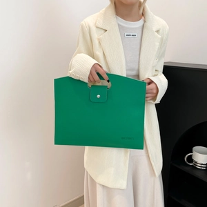 Bolso de mano verde en cuero texturizado con asa recortada y cierre metálico elegante