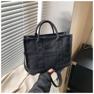 Detail of black canvas tote bag showing thick fabric texture and metallic rivet accents