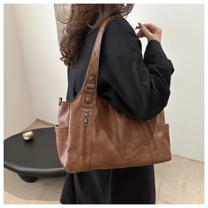 Detail view of large brown faux leather tote bag with side pocket and zipper accents