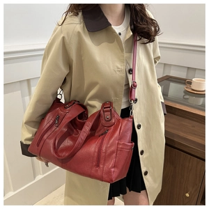 Detail of red large tote bag with metallic zipper and crossbody strap on female model