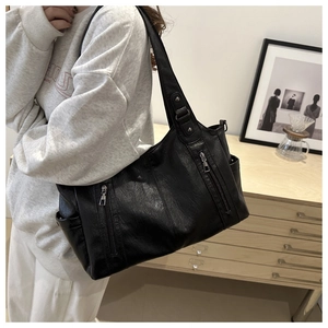 Detail of lychee textured black tote bag showing side zipper pockets and soft leather material