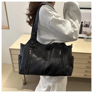 Detail of black pebbled leather tote bag with dual vertical zipper pockets and sturdy handles
