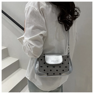 Close-up of gray canvas underarm bag with silver leather, polka dots and bow embroidery