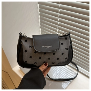 Detailed view of women's shoulder bag featuring bow print and leather strap attachment