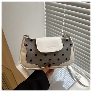 Detail of grey canvas and white leather shoulder bag with black polka dots and bow