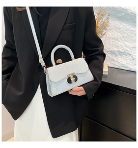 Detail of light blue crossbody bag with silver glitter flap and golden circular lock buckle