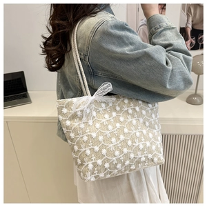 Détail du sac cabas tissé avec broderie en dentelle fleurie blanche et un nœud délicat