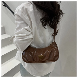 Detail of dark brown glossy pleated shoulder bag with gold triangular metal logo