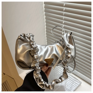 Detail of silver metallic crescent bag with pleated handle and triangle metal logo