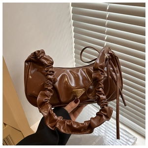 Detailed view of brown glossy ruched bag with a triangular logo and scrunchie strap