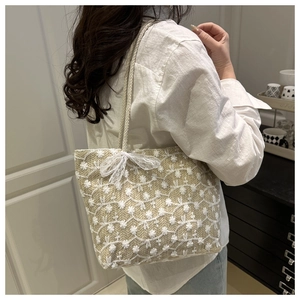 Close-up of beige woven tote bag with white floral embroidery and lace bow details