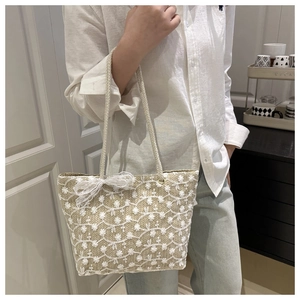 Gros plan du sac cabas en paille avec broderie florale en dentelle et nœud décoratif