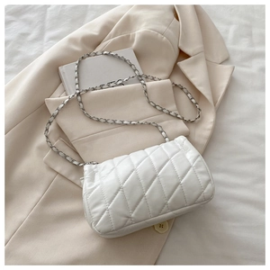 Detail of white quilted handbag with silver chain strap on off-white suit jacket