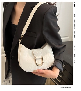 Detail of white moon-shaped bag with marble texture and golden U-shaped buckle closure
