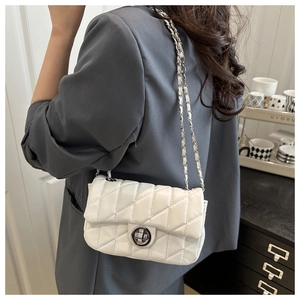 Close-up of white quilted chain bag with silver twist lock on a grey blazer outfit