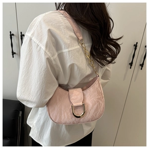 Detail of pink crescent bag with marbled pleats and golden chain strap on a shoulder