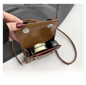 Internal view of brown leather mini crossbody bag showing space for lipstick and makeup