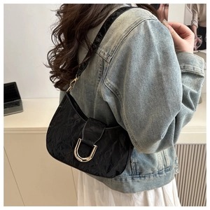 Detail of black pleated texture shoulder bag with silver U-shaped metal buckle