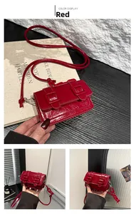 Detail view of red mini crossbody bag with glossy finish and double buckle texture