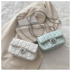 Close-up of white and mint green quilted square bags with silver twist locks on beige blazer