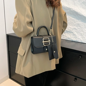 Black pebbled leather tote bag with gold hardware and mini pouch on khaki suit model