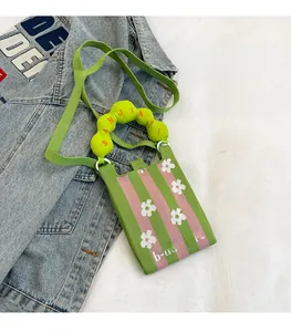 Detalle del mini bolso de punto verde y rosa con motivos florales y texto b-daygift