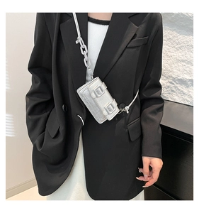 Mini silver laser crossbody bag with metallic texture and chain strap on a black blazer