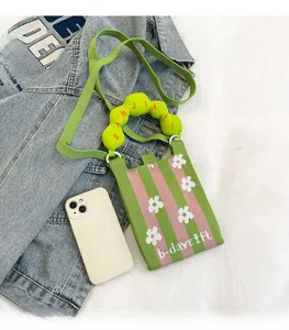 Detalle del mini bolso bandolera de punto con rayas rosa verde y patrón de flores