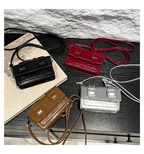 Flat lay of four colorful mini satchel bags in shiny patent leather with double straps