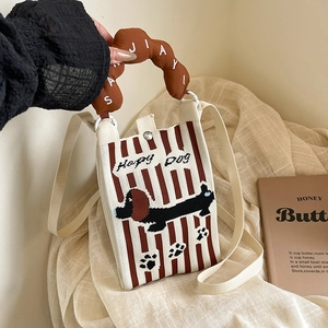 Detalle del bolso bandolera de punto a rayas con bordado de teckel y texto de Hapy Dog