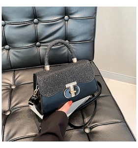 Detail of black sequined flap with gold T-shaped lock on luxury leather crossbody bag