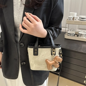 Mini sac cabas beige minimaliste avec poignées noires et pendentif chien brun
