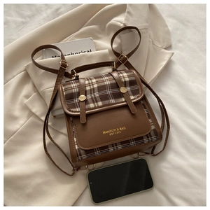 Detail des Vintage-Karo-Rucksacks mit brauner Lederklappe, Goldlogo und Schnallenverschluss