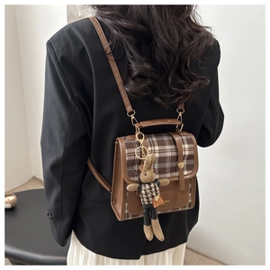 Detail of vintage brown plaid mini backpack with cute rabbit pendant on a model