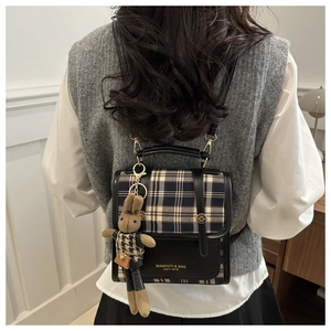 Detail of checkered casual backpack with cute bunny charm on a female model back