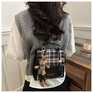 Detail of British style plaid backpack with leather trim and cute rabbit pendant