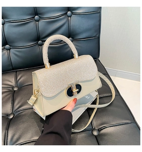 Detailed macro view of cream leather texture and gold buckle on a stylish mini handbag