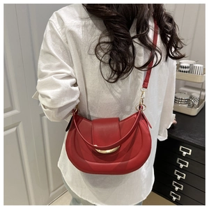 Détail du sac de selle en cuir rouge avec boucle dorée en demi-lune sur le mannequin