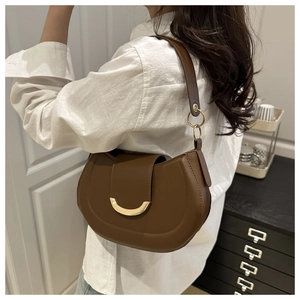 Detail of a brown half-moon underarm bag with a stylish golden crescent metal buckle