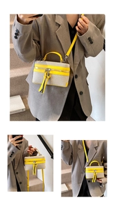 Detail of trendy small square bag with yellow leather trim and long fringed tassels