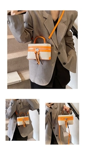 Detail of beige canvas and orange leather box bag with dual zippers and adjustable strap