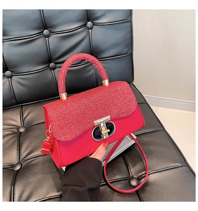 Close-up of red sequined handbag with gold clasp detail on black leather background