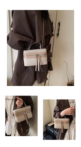 Detail view of canvas and leather box bag with dual tassels and crossbody strap