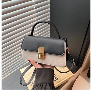Detail of color-block handbag with black leather flap, woven body, and gold twist lock