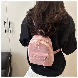 Vue détaillée de la texture en velours côtelé du mini sac à dos rose et de sa fermeture