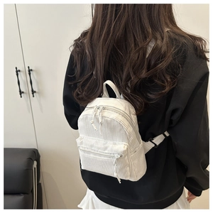 Détail d'un mini sac à dos blanc en velours côtelé avec tirettes de zip tissées