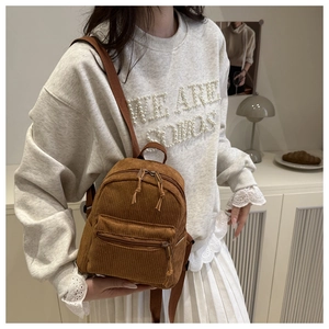 Detail eines Mini-Rucksacks aus karamellfarbenem Cord mit verstellbaren Trägern im Alltag